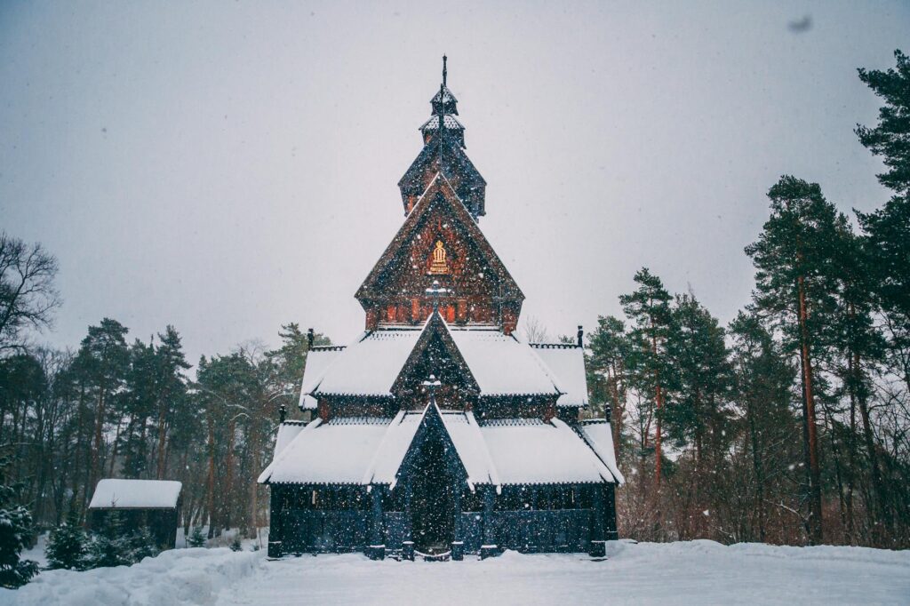 Breathtaking view of a traditional Norwegian stave church surrounded by snow-covered trees in Oslo during winter.