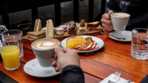 Enjoy a cozy coffee moment with assorted desserts on a wooden table.